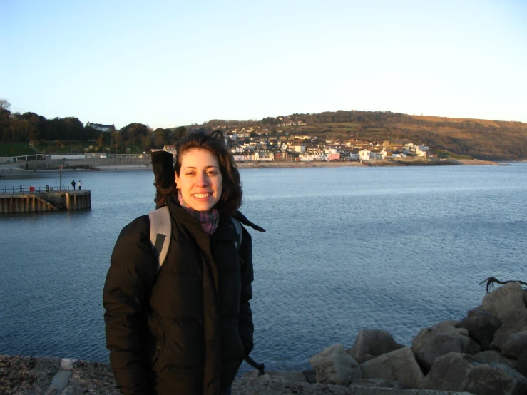 a smiling lady in a jacket by the sea