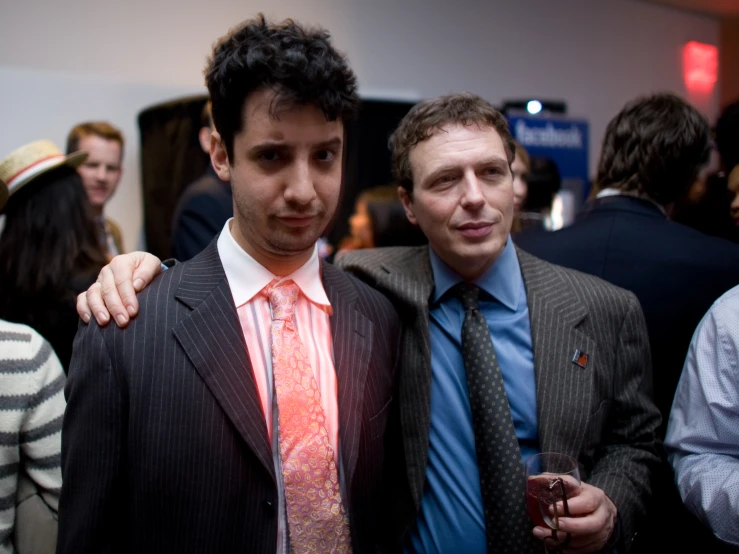 two men are standing side by side, wearing suits and ties