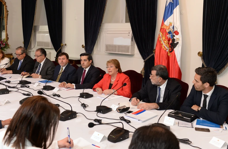 a number of people sitting at a table with microphones