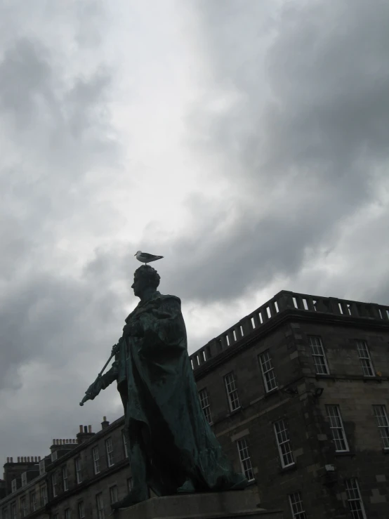 a statue on the edge of a walkway next to a tall building