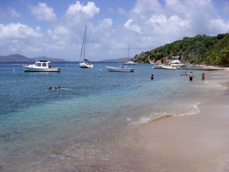 sail boats in the clear blue water near an island