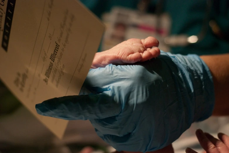 a person in blue sterile gloves holds out their hand