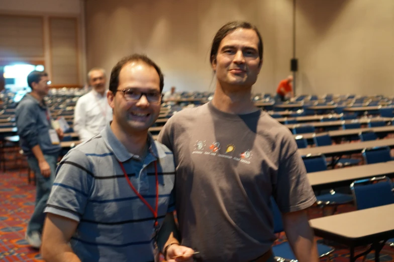 two men standing next to each other in an auditorium