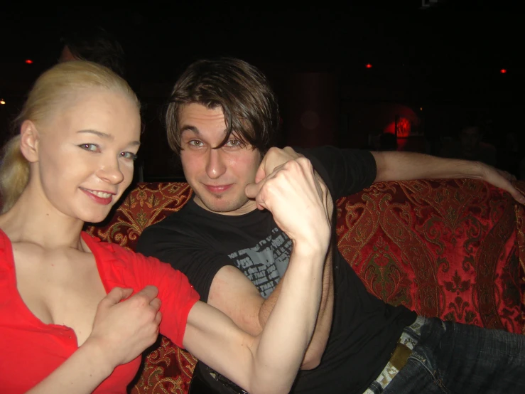 a man and woman sitting on a red chair with their arm around each other