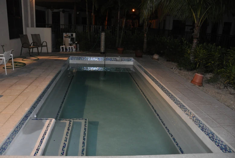 an outdoor pool at night next to lawn chairs