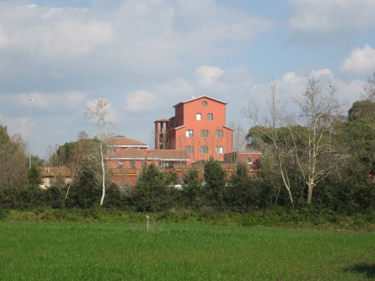 a green field that has a large red building in it