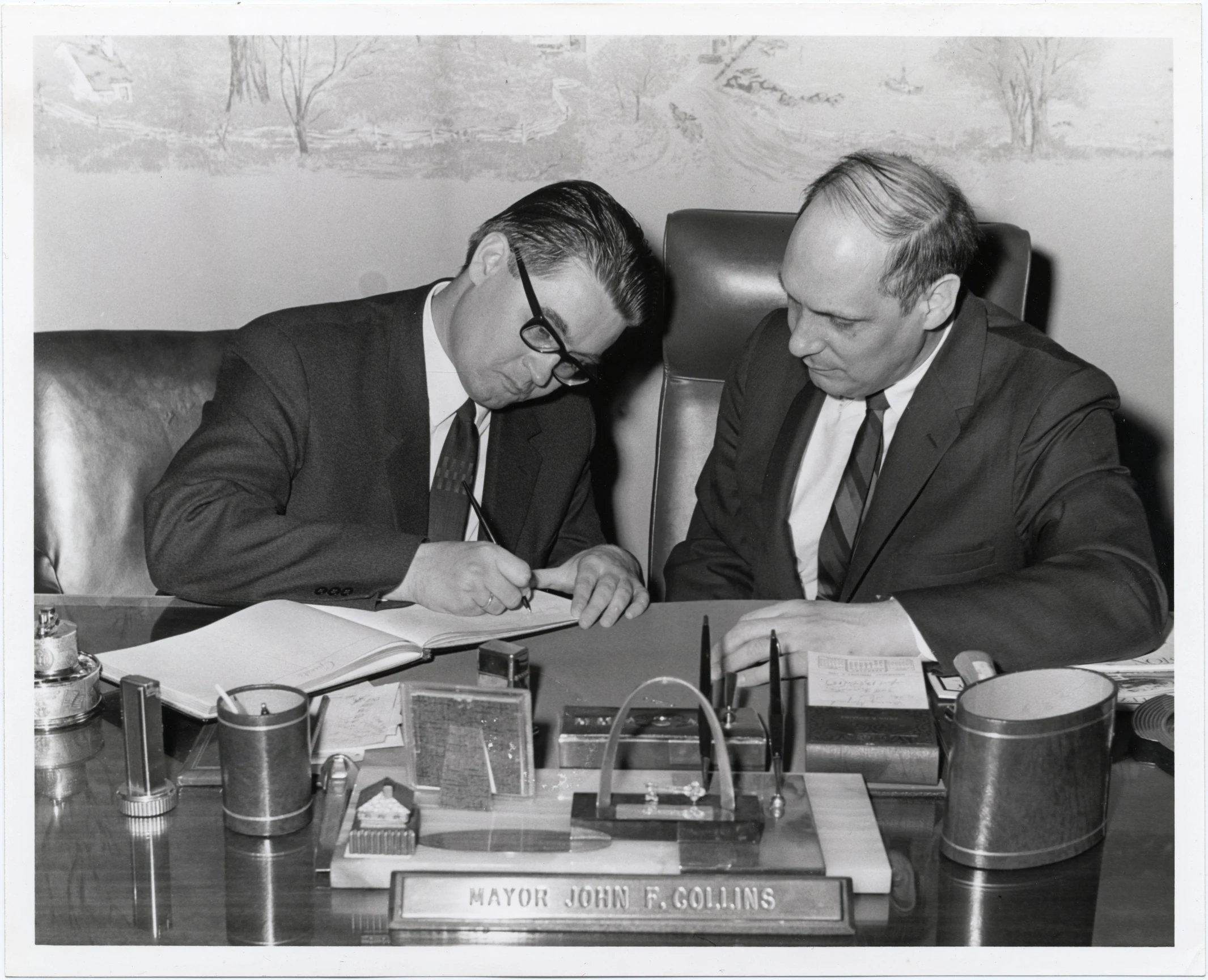 a man sitting at a desk in a business meeting with another man