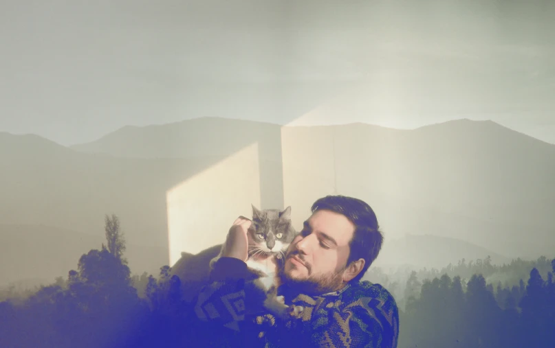 man in a dark scarf holding up his cat