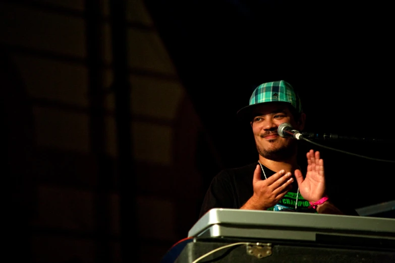 a man standing in front of a microphone while wearing a hat