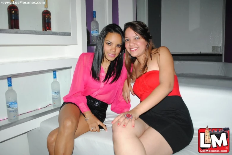 two beautiful young ladies sit together on the bed