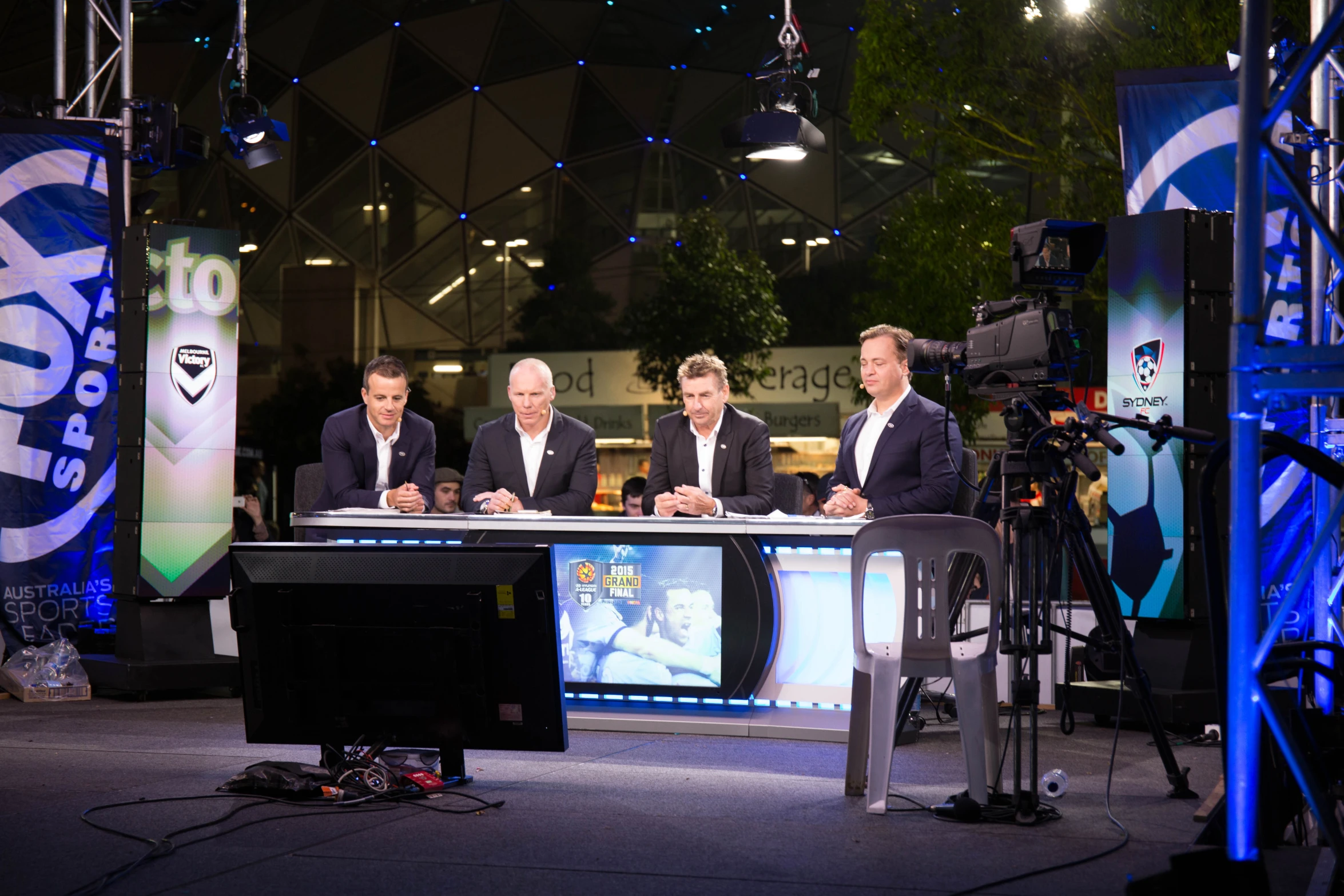 three men sitting at a table on a tv set