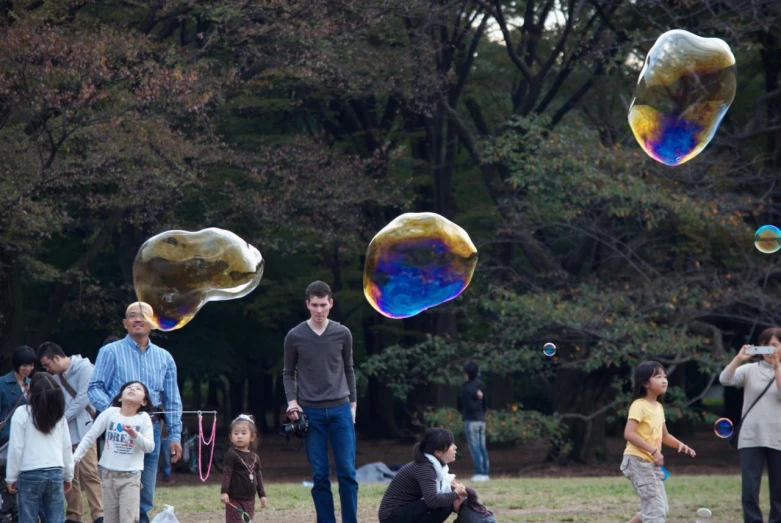 a group of people playing with bubbles in the park