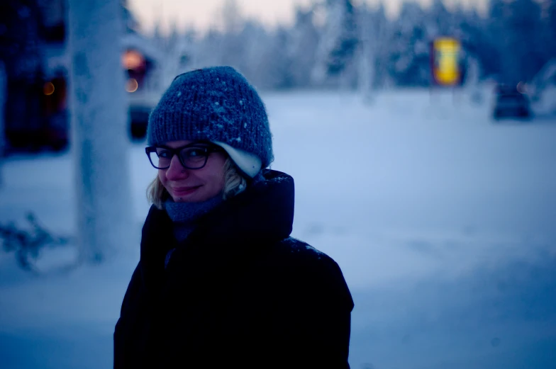 a young woman standing on top of a snow covered field