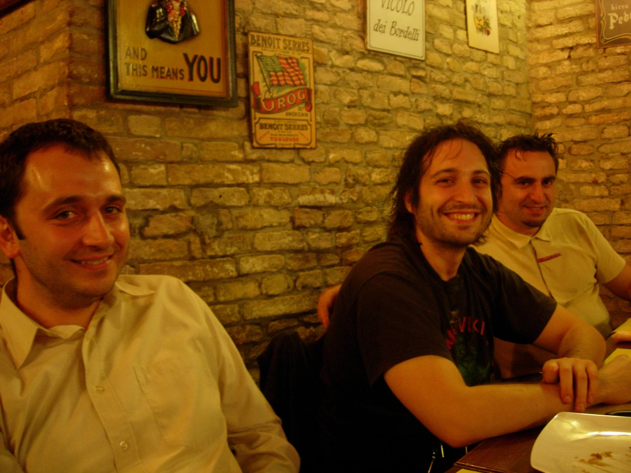 three men sitting at a bar with their arms crossed