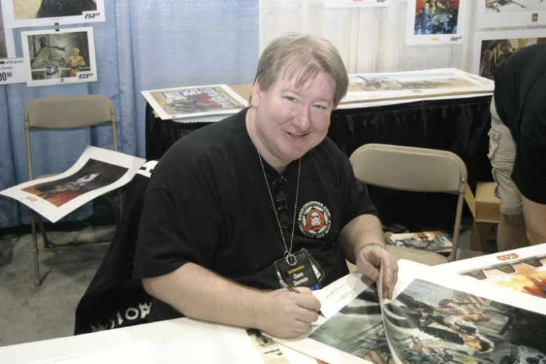 a man poses with his comic book in front of the press table