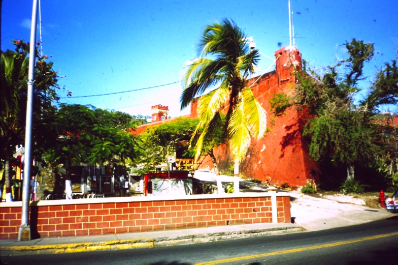 a red brick building with a white fence and a palm tree