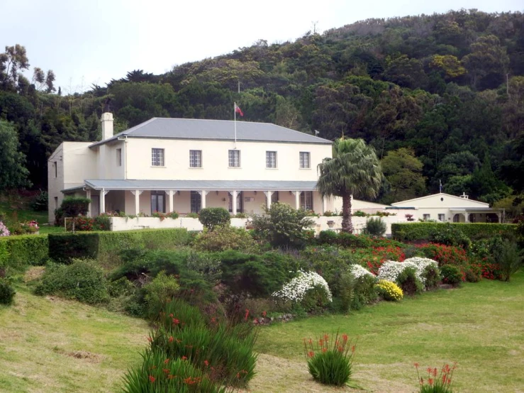 two large houses on a hill behind a garden