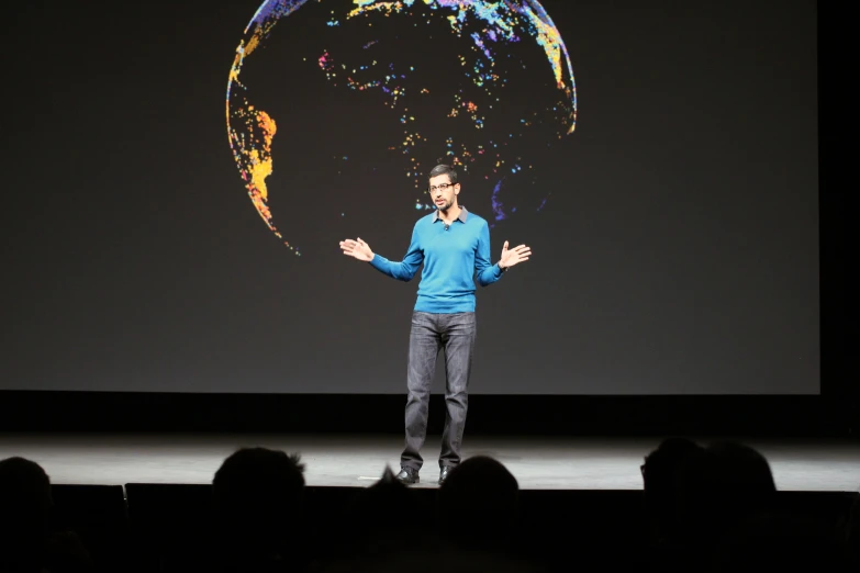 a person standing in front of a stage with a laptop on his hand