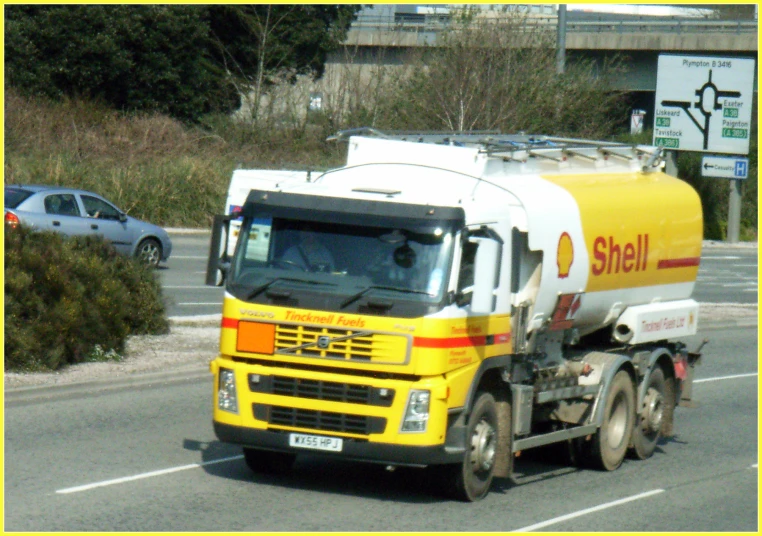 a yellow truck moving along a road in the street