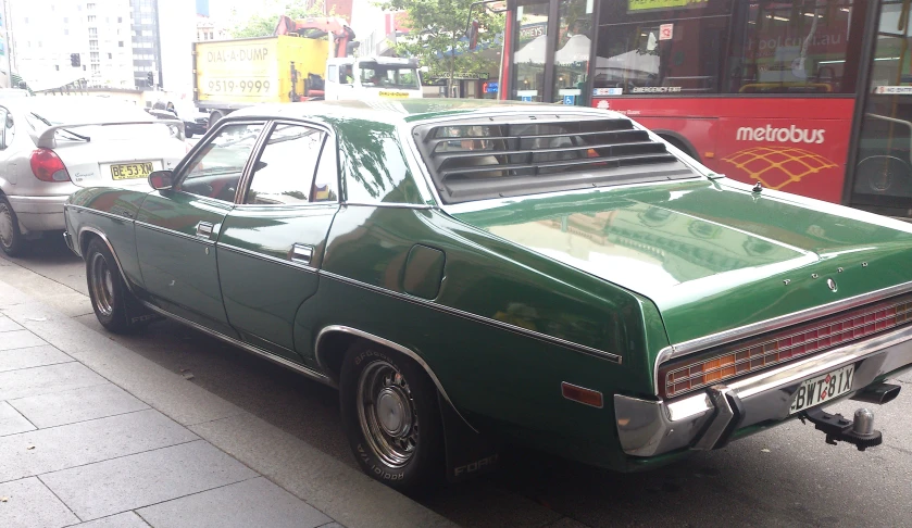 a green old fashioned station wagon is parked on the side of the road