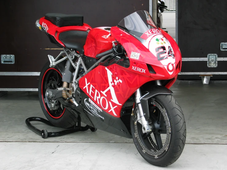 a red motorcycle parked on top of a garage floor