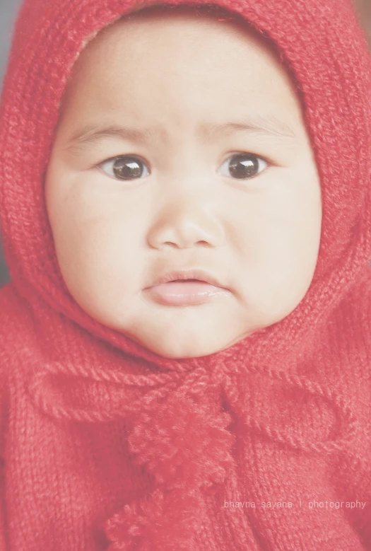 a baby in a red sweater with a hood on