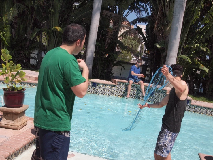 two men are by the pool playing with a net