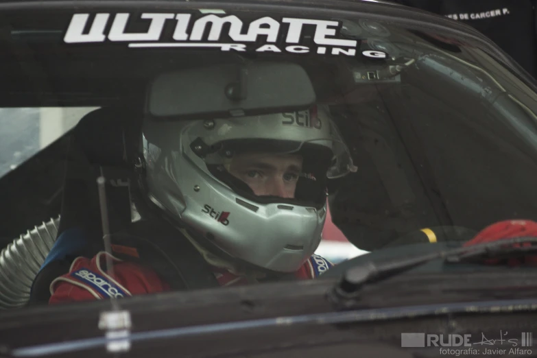 man in racing gear sitting in a car