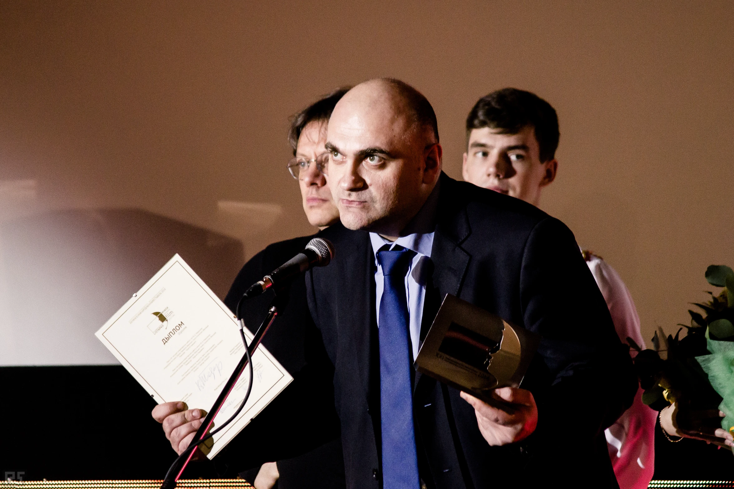 a person standing with a microphone and papers