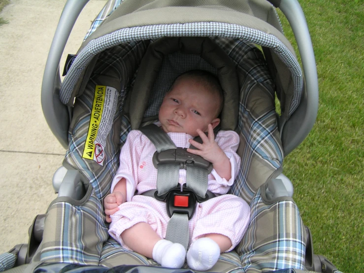a baby sitting in a stroller holding onto his thumb
