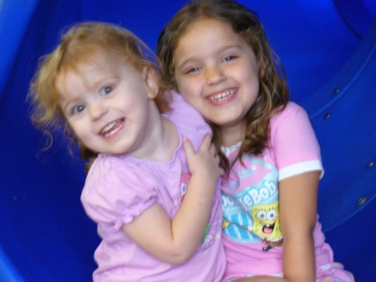 two little girls sitting in a blue tube