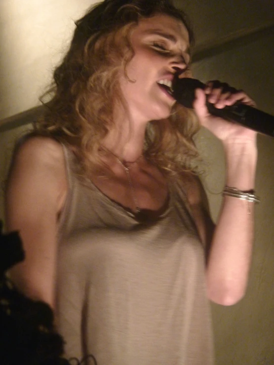 a woman is singing into a microphone with long hair