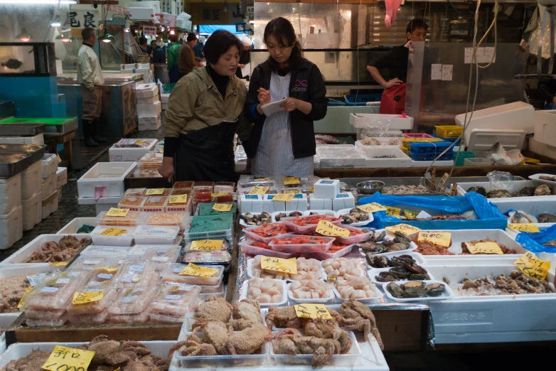 two woman standing near a table full of food