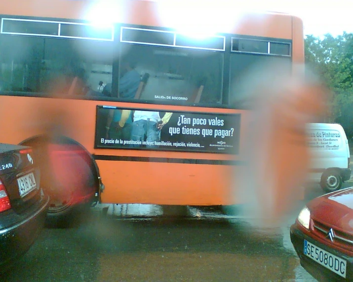 people walking by an orange and black bus