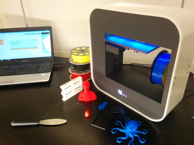 two open laptops sit on a desk, one displaying a blue light