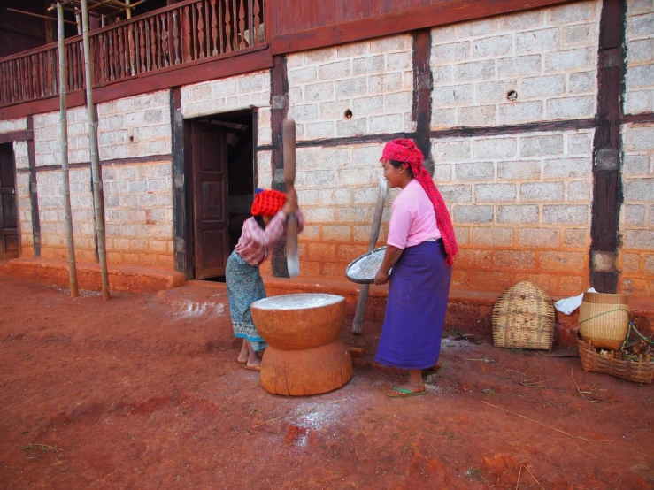 two women standing outside and holding a large piece of wood