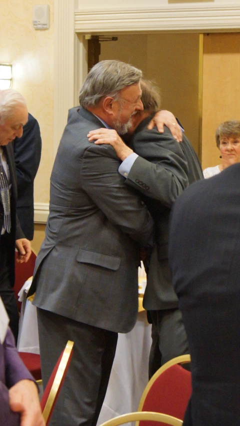 two older men emcing in a large room