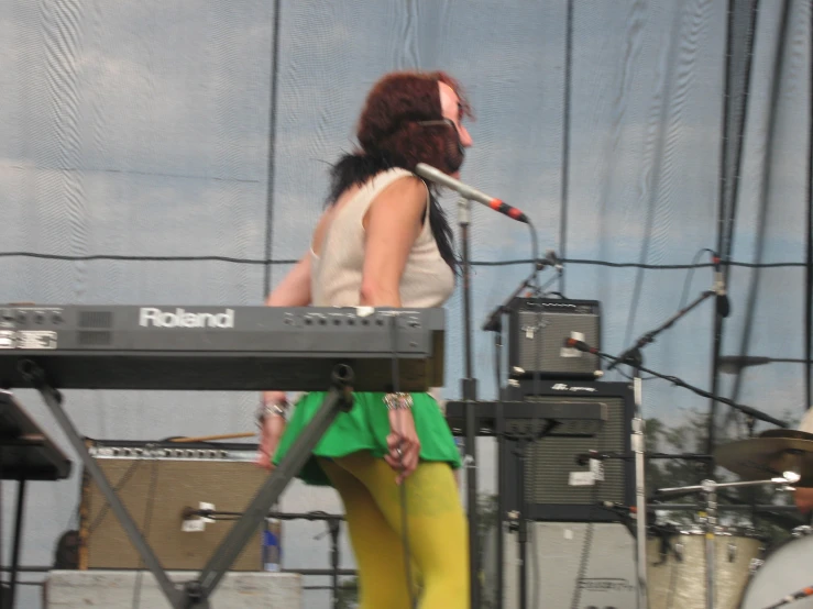 a girl is playing a keyboard while standing on stage