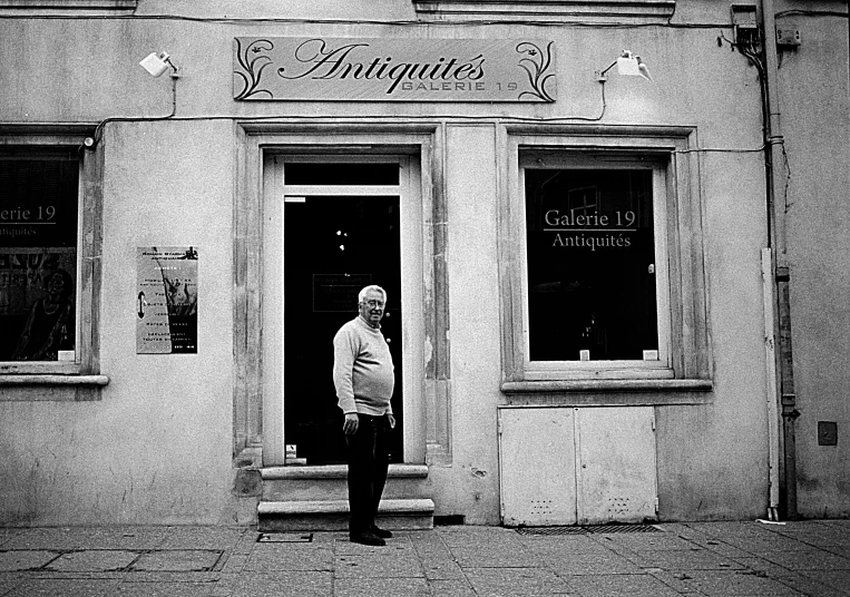 man stands outside an antique store front