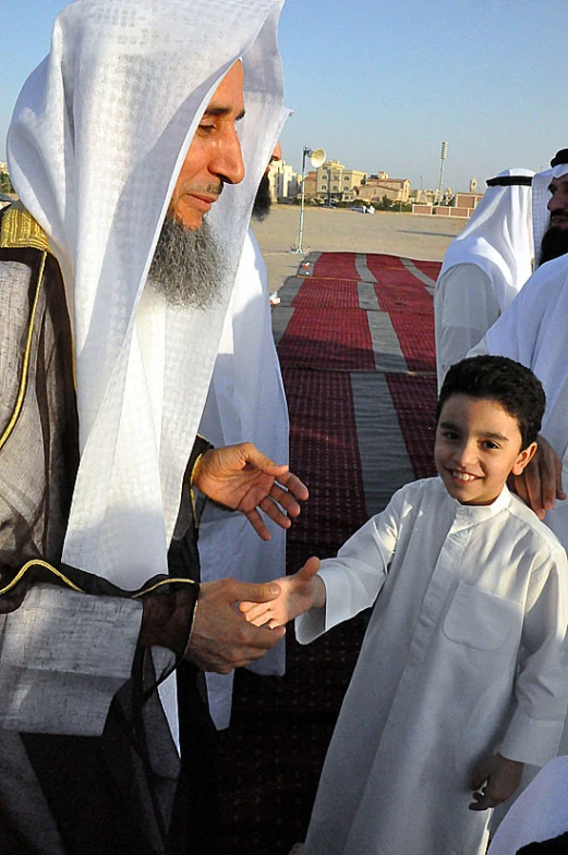 a man holding his child as others gather to pray