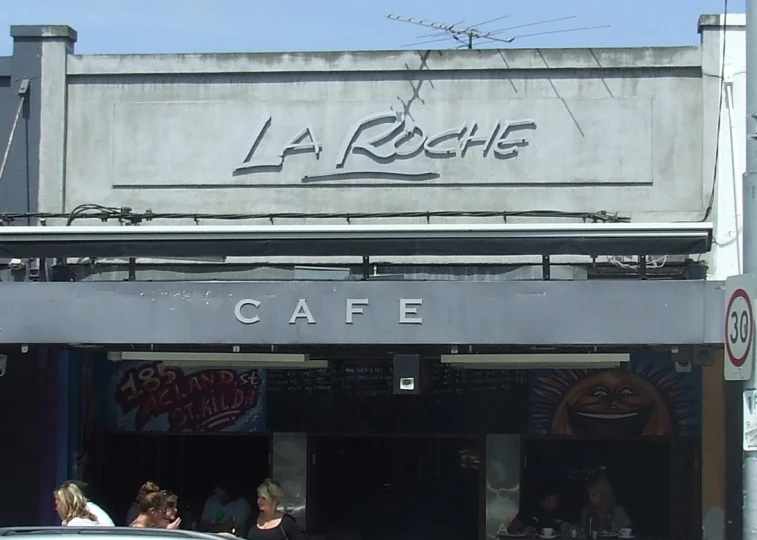 a large group of people stand outside a cafe