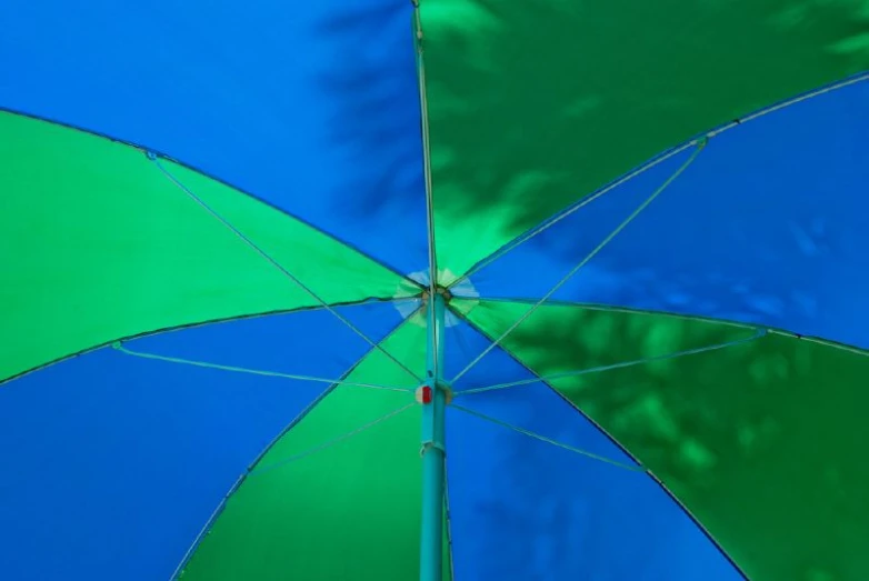 a blue and green umbrella with trees in the background
