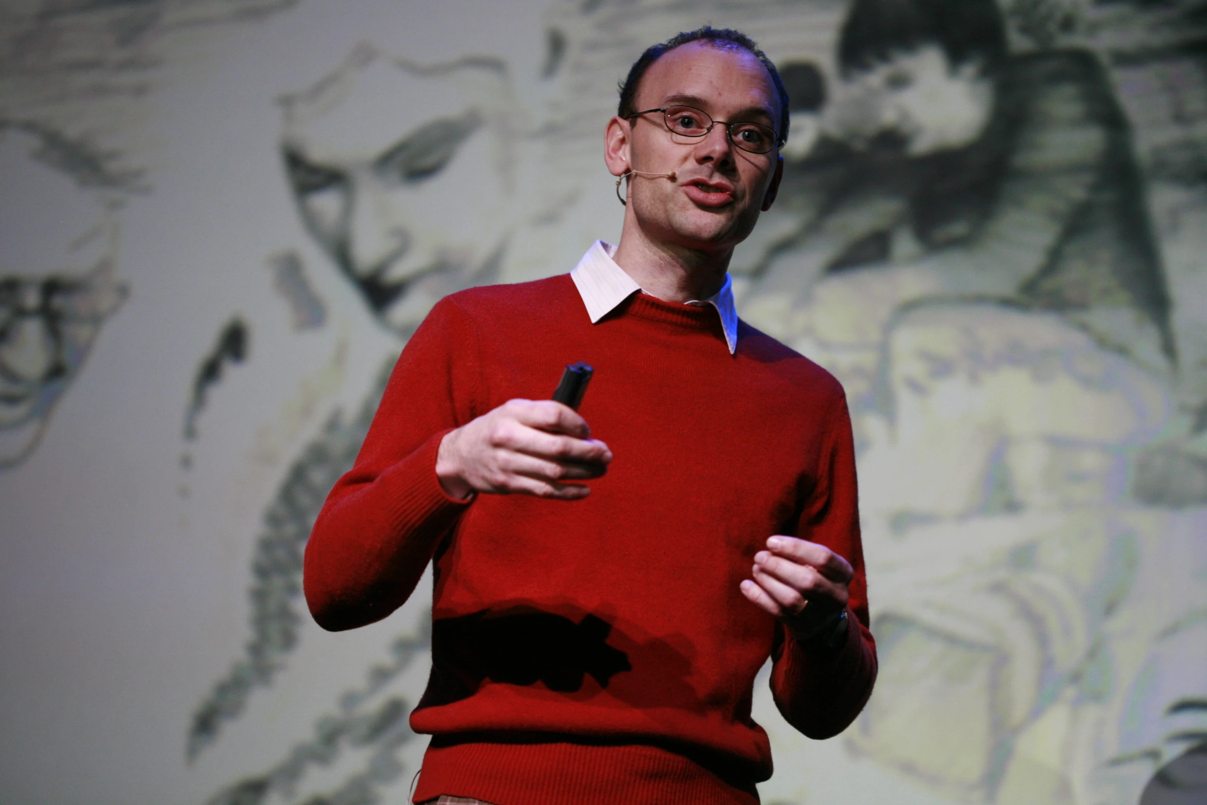 the man is wearing a red sweater, writing on his electronic device