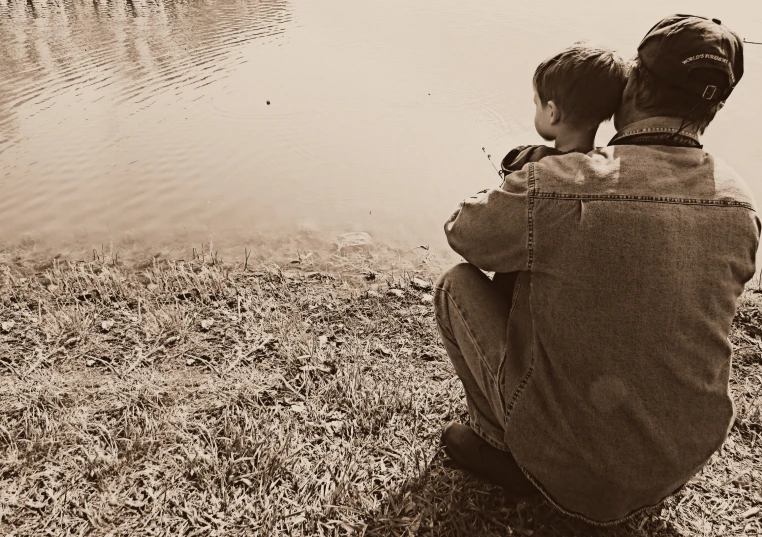 two people that are sitting by some water