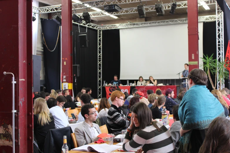 there are many people sitting at tables at a meeting