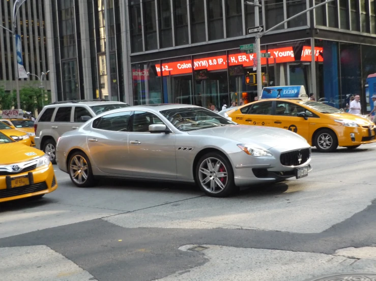 two yellow taxis are driving down a street next to a building