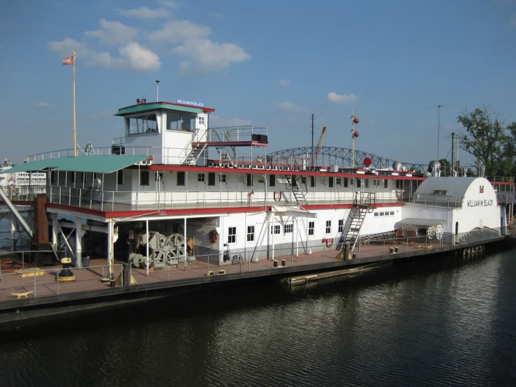 the boat has several decks and is docked near the water