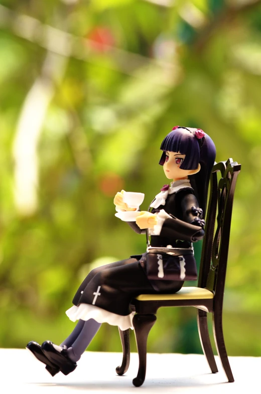 a small doll is sitting on a chair holding food
