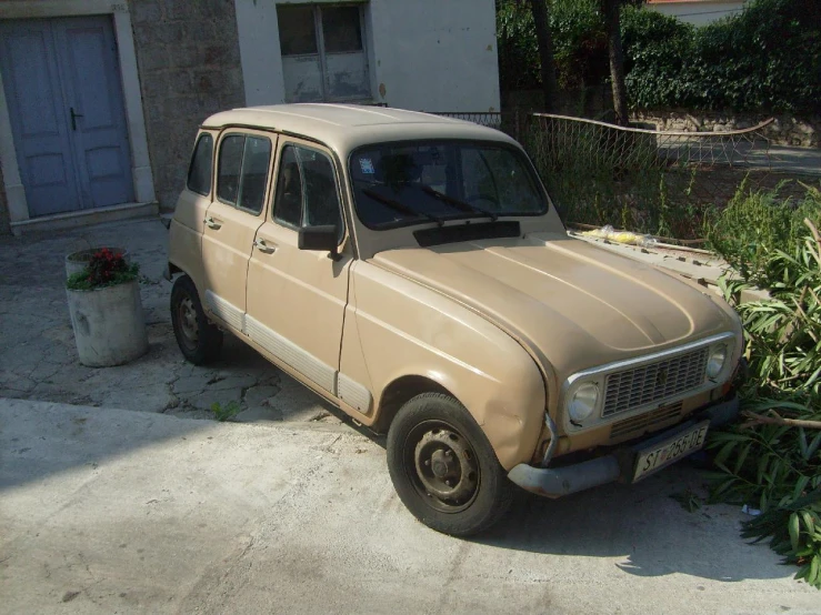 an older beige car sitting next to a garage