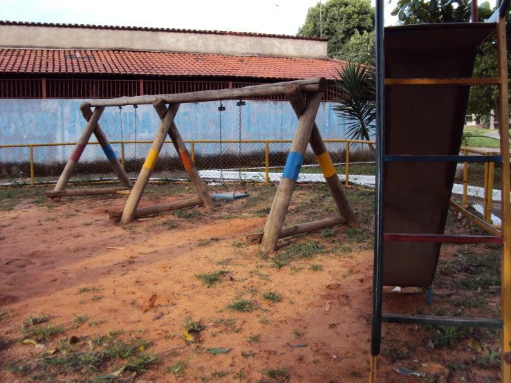 a brown wooden swing set and some sort of blue house